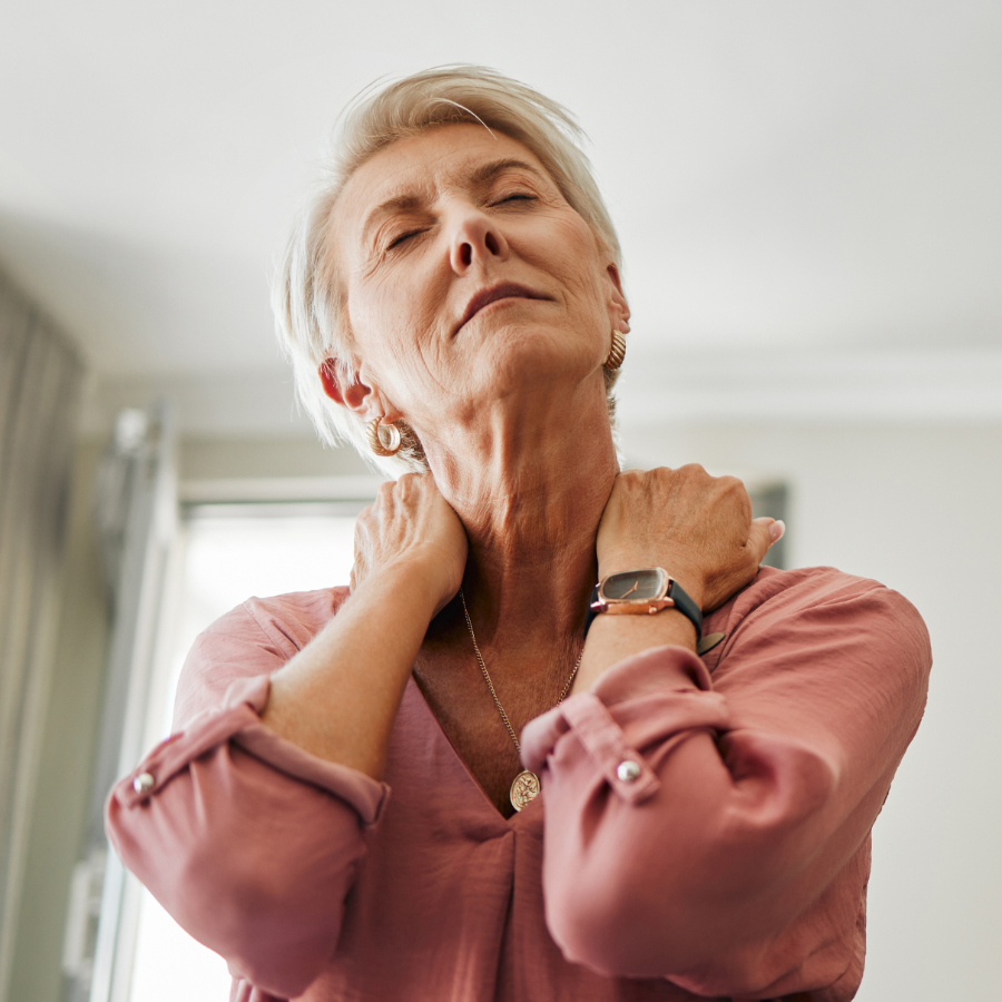 Older woman holder her neck with both hands in discomfort.